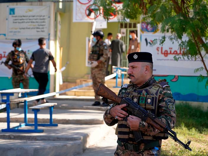 Policemen stand guard outside a polling station during parliamentary elections, in Mosul, Iraq, Sunday, Oct. 10, 2021. Iraq closed its airspace and land border crossings on Sunday as voters headed to the polls to elect a parliament that many hope will deliver much needed reforms after decades of conflict and mismanagement.