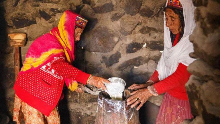 Dentro de sus cabañas, Annar (izquierda) y Thai Bibi (derecha) vierten yogur en un tambor tradicional para hacer mantequilla