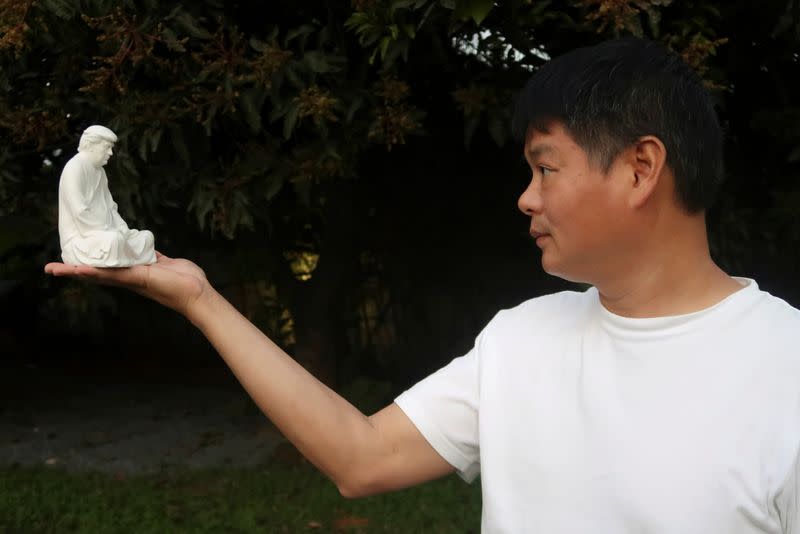 Chinese designer Hong Jinshi poses with his statue in Xiamen