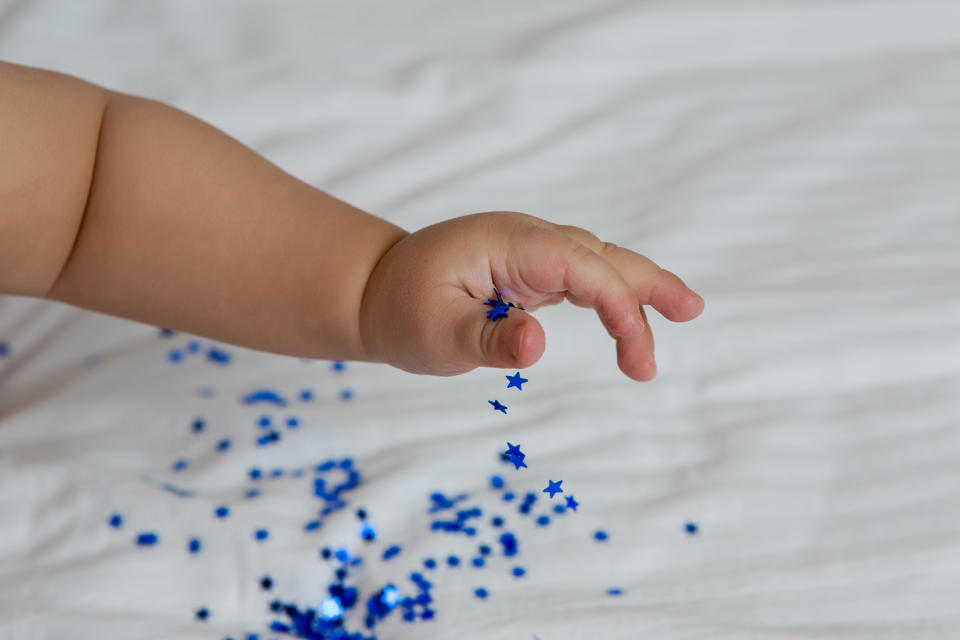 child is sitting on the bed with blue sequined stars