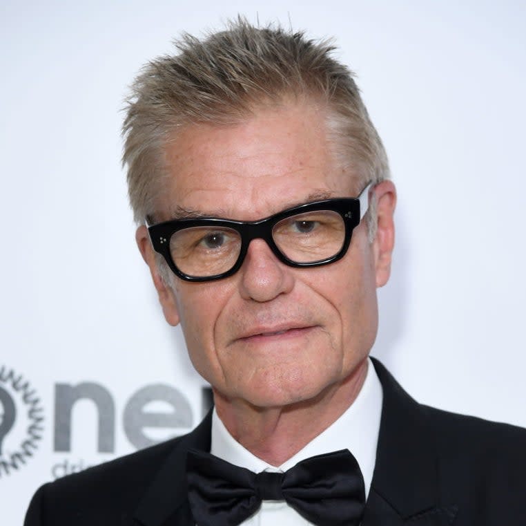 Harry Hamlin wearing a classic black tuxedo with a black bow tie and black-rimmed glasses at a red carpet event