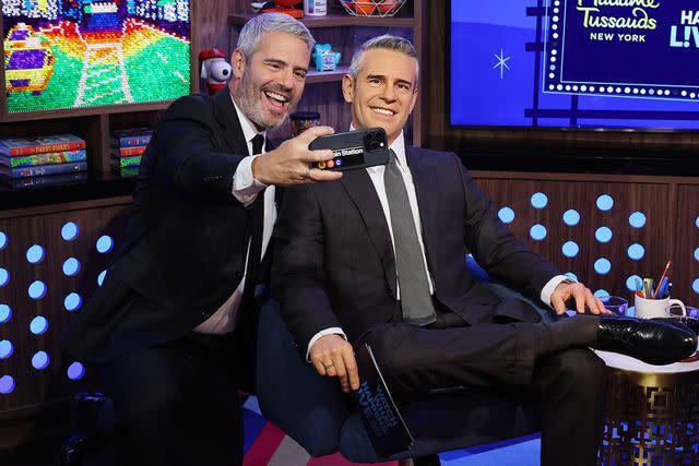 <p>Cindy Ord/Getty </p> Andy Cohen takes a selfie with his Madame Tussauds wax figure