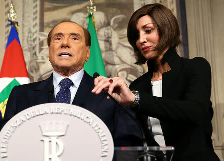 Forza Italia party senator Anna Maria Bernini fixes the microphone for Silvio Berlusconi as he arrives to speak with the media during the second day of consultations with Italian President Sergio Mattarella at the Quirinal Palace in Rome, Italy, April 5, 2018. REUTERS/Alessandro Bianchi