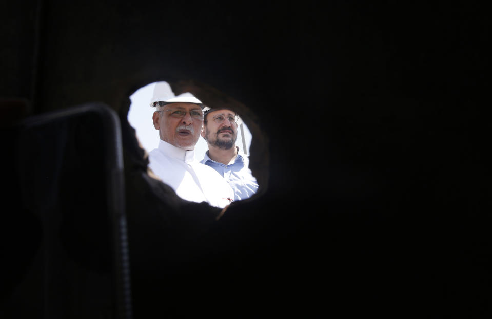 In this photo opportunity during a trip organized by Saudi information ministry, Aramco workers are seen through a hole in a damaged pipe in the Khurais oil field in Khurais, Saudi Arabia, Friday, Sept. 20, 2019, after it was hit during Sept. 14 attack. Saudi officials brought journalists Friday to see the damage done in an attack the U.S. alleges Iran carried out. (AP Photo/Amr Nabil)