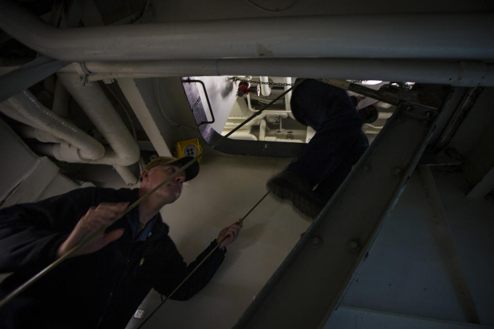 Navy Chaplain Lt. Cmdr. Ben Garrett makes his way up to the next deck using a ladder well inside the USS Bataan on Monday, March 20, 2023. The steep stairs within the ship are the only way to move between decks. (AP Photo/John C. Clark)