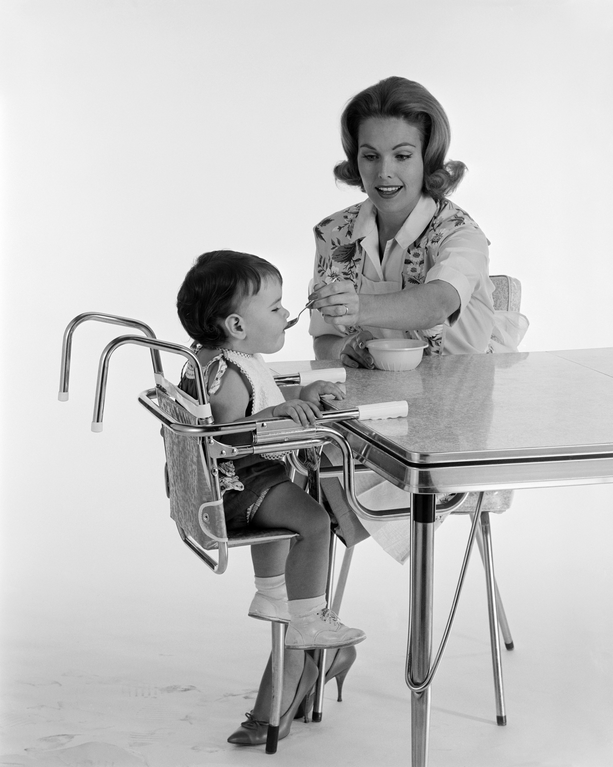 vintage photo of mother feeding baby in high chair