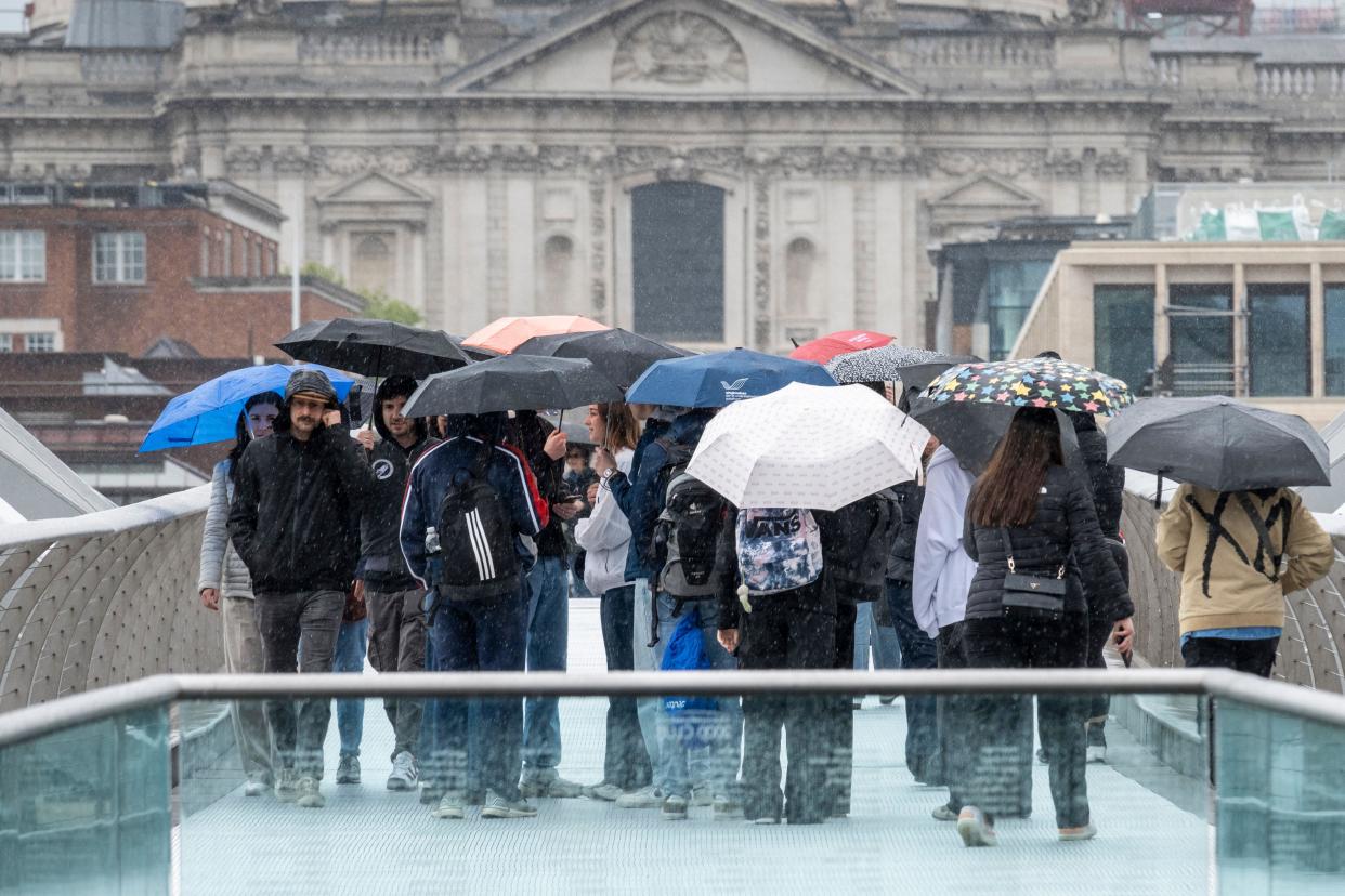 London, UK.  6 May 2024.  UK Weather – People cross the Millennium Bridge, with St Paul's Cathedral behind, in the rain on a wet early May Bank Holiday Monday.  The Met Office forecast is for rain in the capital for most of the day.  Credit: Stephen Chung / Alamy Live News
