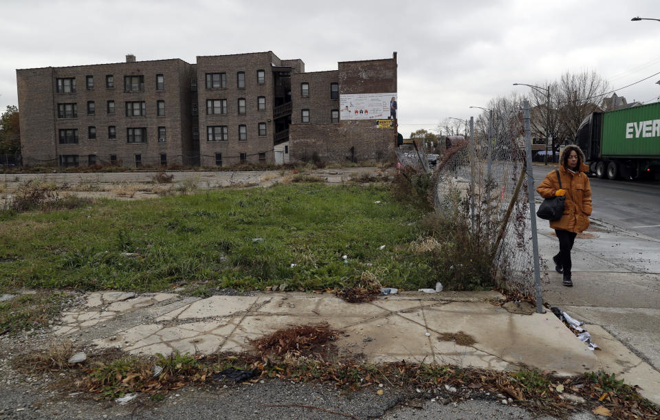 A pedestrian walks past an abandoned lot on a street on the South Side of Chicago that is part of the 6th Police District. Officers there marked a milestone this fall when they recovered their 1,000th gun for the year. The community has neat bungalows and apartment buildings, mom-and-pop stores as well as signs of despair, including weed-filled lots and shuttered houses. (AP Photo/Nam Y. Huh)