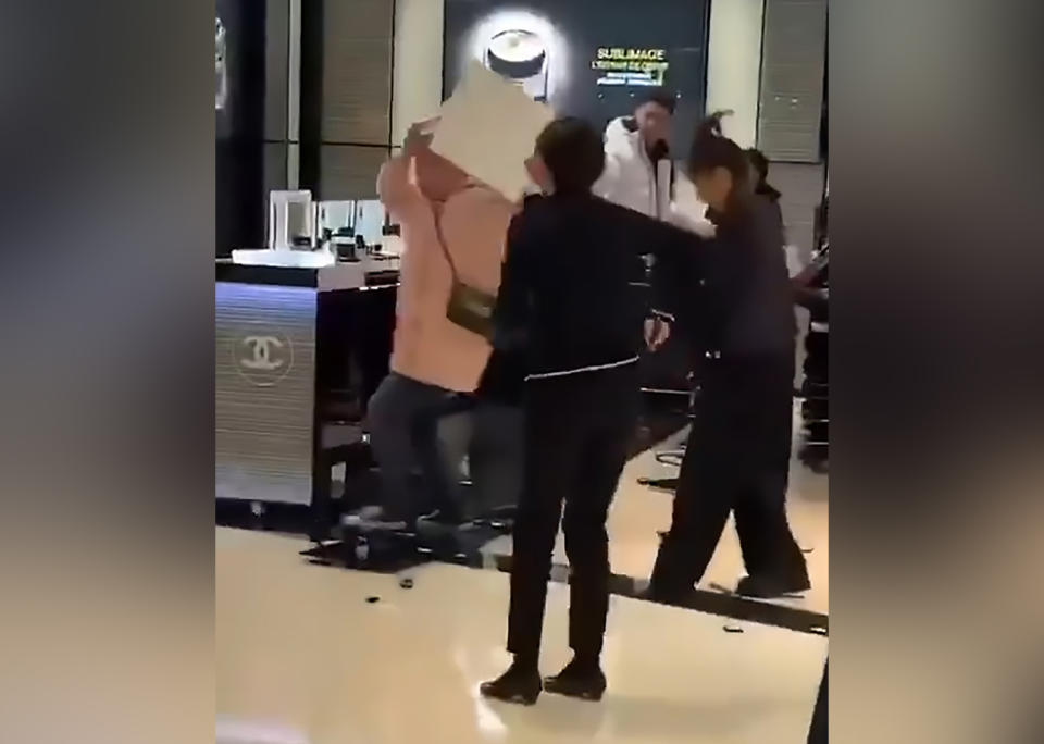 A woman picks up a part of the Chanel makeup counter and slams it against the tiles. Source: Australscope