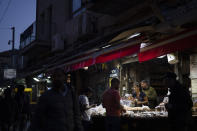 People buy bread at a shop in the Mahane Yehuda market in Jerusalem, Sunday, April 14, 2024. Israel on Sunday hailed its air defenses in the face of an unprecedented attack by Iran, saying the systems thwarted 99% of the more than 300 drones and missiles launched toward its territory. (AP Photo/Leo Correa)