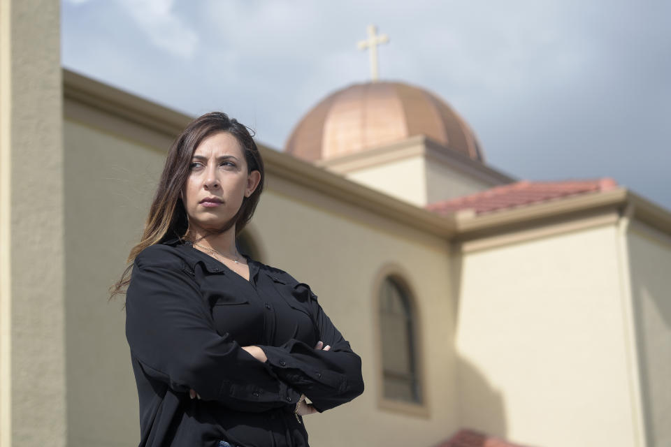 Sally Zakhari stands in front of the St. Mary & Archangel Michael Coptic Orthodox Church, Monday, Aug. 24, 2020, in Oviedo, Fla. Zakhari has alleged, including in a police report and to Coptic Church officials, that a Coptic priest visiting Florida in the late 1990s, Reweis Aziz Khalil, sexually abused her when she was 11 or 12. Khalil was stripped of his priesthood in July; he denied the allegations through his attorney. (AP Photo/Phelan M. Ebenhack)