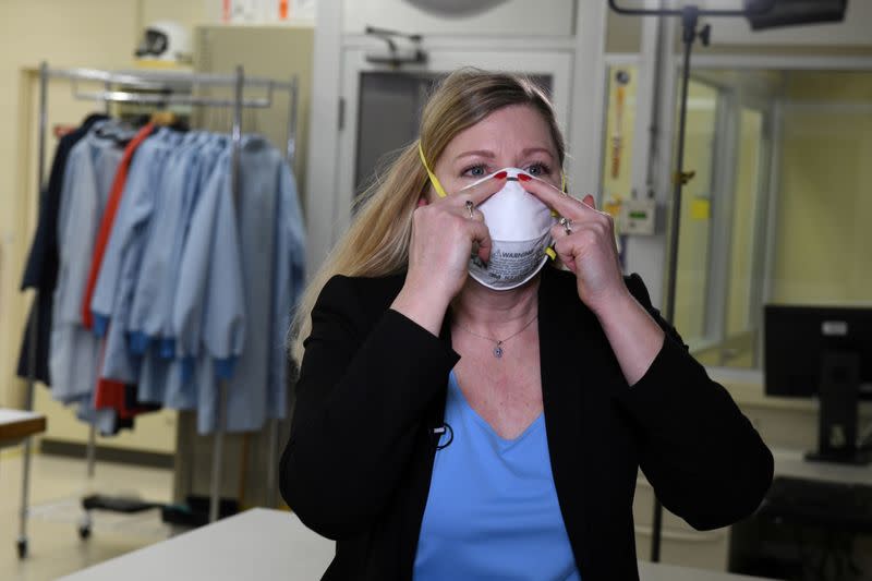 FILE PHOTO: Dr. Nicole McCullough, a global health and safety expert at 3M, demonstrates the correct way to put on a N95 respiratory mask at a laboratory of 3M in Maplewood, Minnesota