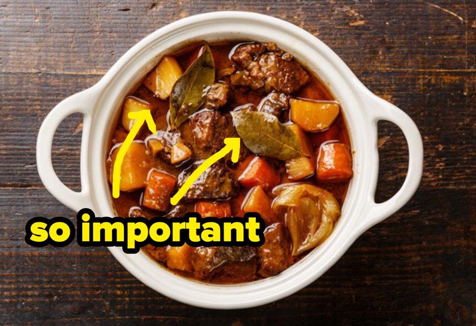 Beef meat stewed with potatoes, carrots and spices in ceramic pot on wooden background with arrows to bay leafs saying so important