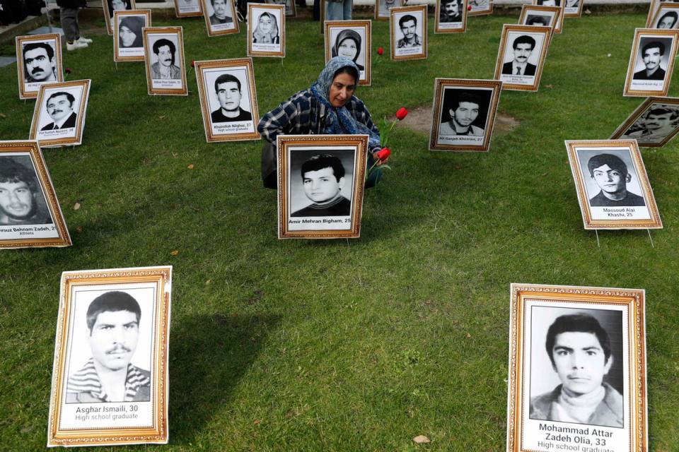 A protester places flowers on a photograph of an executed man during a demonstration to protest against the inaugeration Ebrahim Raisi in London in 2021 (AFP via Getty Images)