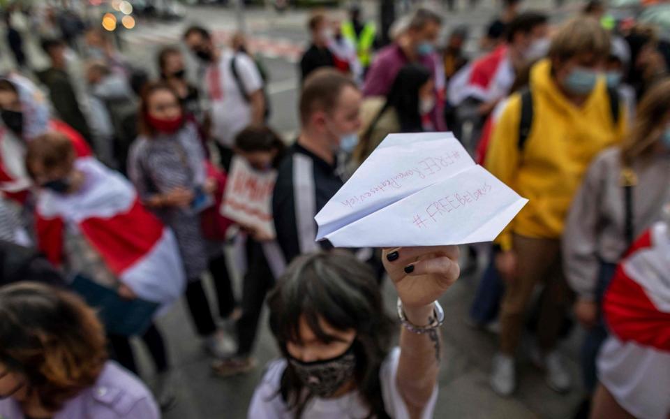 A demonstrator holds up a paper plane with the lettering 'Free Belarus' and 'Free Roman Protasevich'