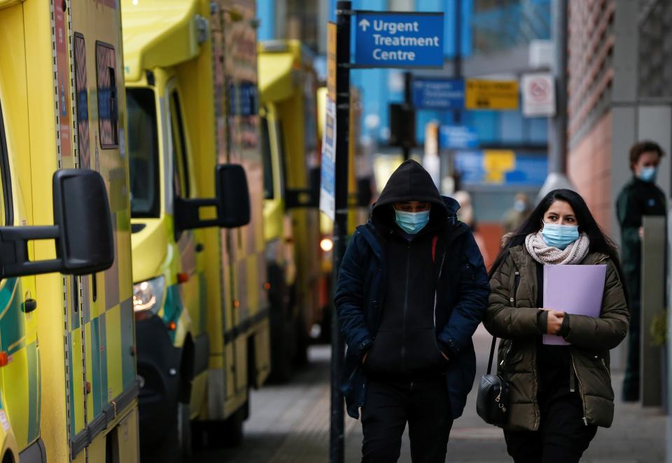 LONDON, Jan. 26, 2021 -- People wearing face masks walk past ambulances at The Royal London Hospital in London, Britain, on Jan. 26, 2021. The total number of coronavirus-related deaths in Britain has surpassed 100,000 after another 1,631 have been confirmed, according to official figures released Tuesday. The total number of coronavirus-related deaths in Britain now stands at 100,162, the data showed. (Photo by Han Yan/Xinhua via Getty) (Xinhua/Han Yan via Getty Images)