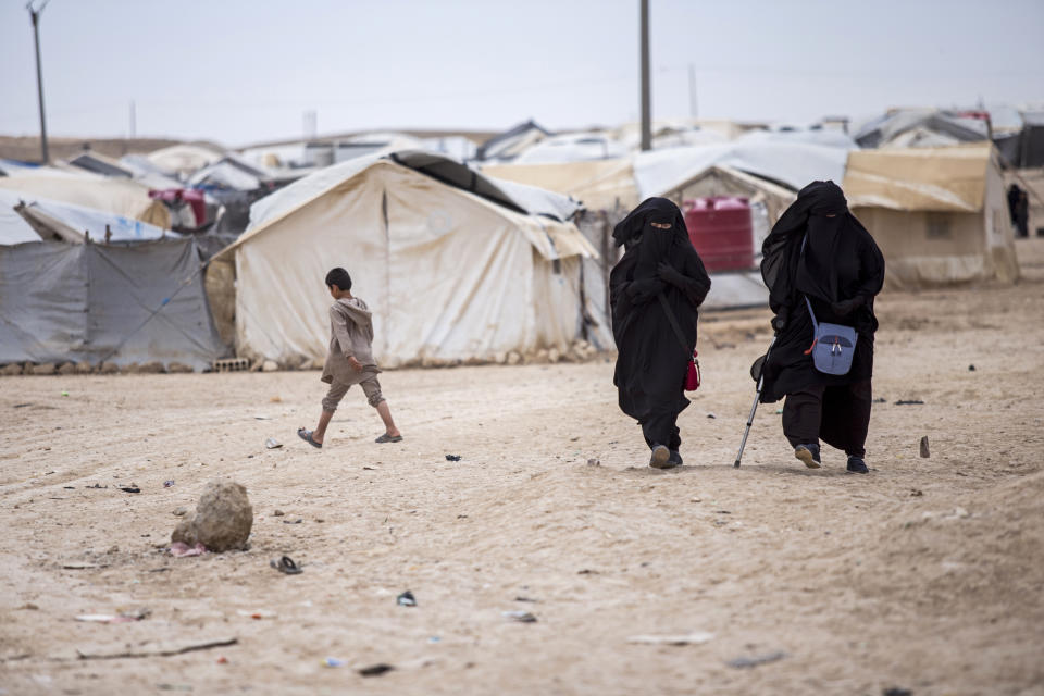 Women walk in the al-Hol camp that houses some 60,000 refugees, including families and supporters of the Islamic State group, many of them foreign nationals, in Hasakeh province, Syria, Saturday, May 1, 2021. Kurdish officials say security has improved at the sprawling camp in northeast Syria, but concerns are growing of a coronavirus outbreak in the facility. (AP Photo/Baderkhan Ahmad)