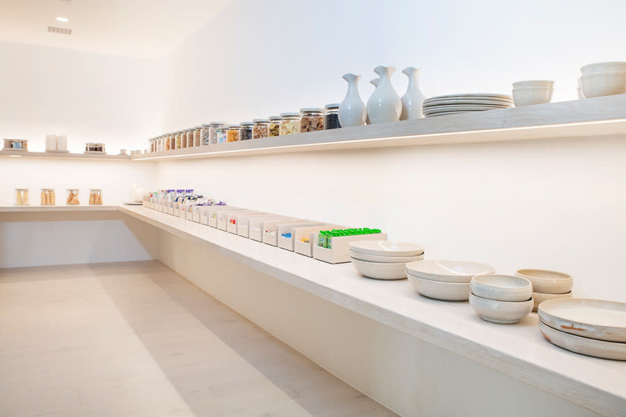 There are now two shelves; the giant glass jars remain, and they're now joined by opened-faced bins as well as stacked plates, bowls, and cups