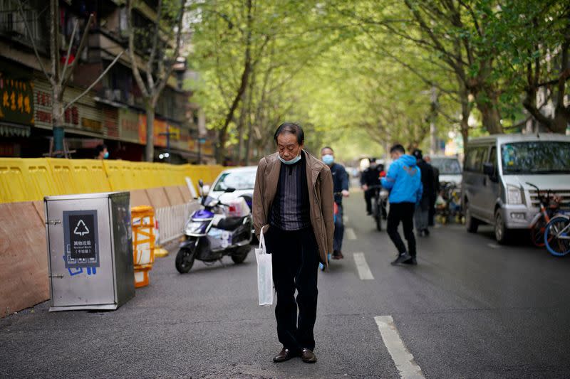 Man with a face mask observes a moment of silence on a street in Wuhan