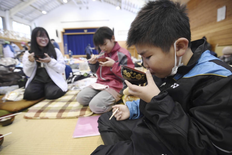 Young evacuees takes a meal together in a shelter in the earthquake-hit Anamizu, Ishikawa prefecture, Monday, Jan. 8, 2024. Thousands of people made homeless overnight are living in weariness and uncertainty on the western coast of Japan a week after powerful earthquakes hit the region. (Kyodo News via AP)