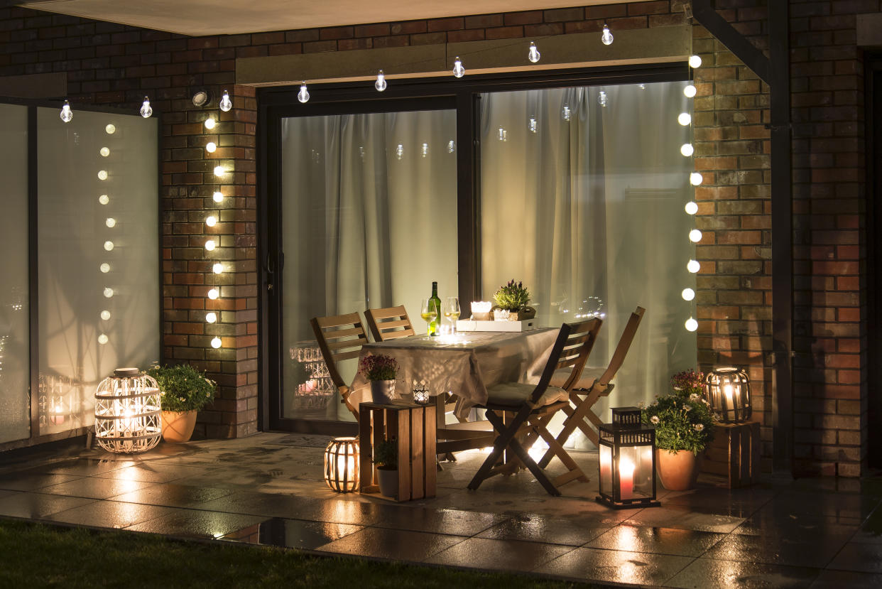  An outside deck at night with an outdoor dining set and string lights 