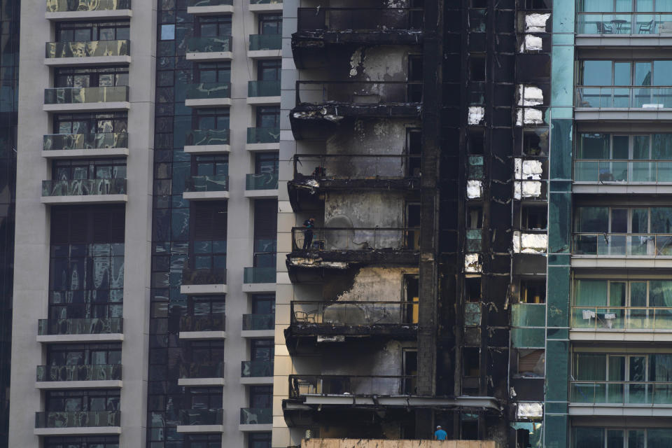 Investigators examine fire damage at the high-rise 8 Boulevard Walk in Dubai, United Arab Emirates, Monday, Nov. 7, 2022. A fire broke out early Monday morning at a 35-story high-rise building in Dubai near the Burj Khalifa, the world's tallest building. (AP Photo/Jon Gambrell)