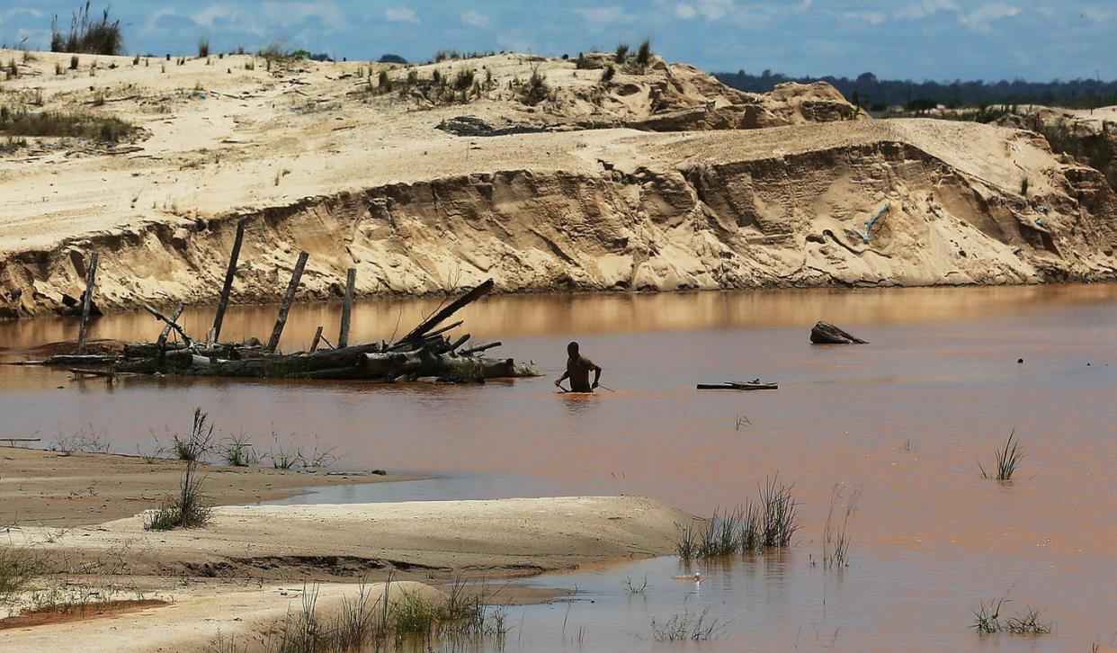 <span class="caption">Artisanal small-scale gold mining polluted this stream and deforested sections of the Madre de Dios area of Peru. </span> <span class="attribution"><a class="link " href="https://www.gettyimages.com/detail/news-photo/miner-walks-through-a-polluted-stream-in-a-deforested-area-news-photo/450562169?adppopup=true" rel="nofollow noopener" target="_blank" data-ylk="slk:Mario Tama/Getty Images;elm:context_link;itc:0;sec:content-canvas">Mario Tama/Getty Images</a></span>