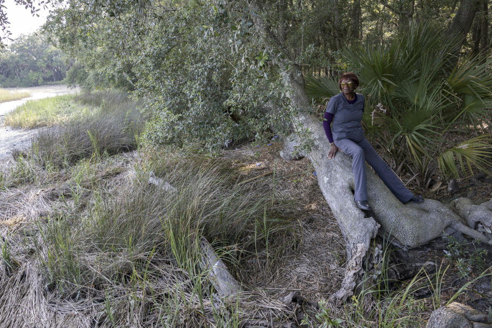 Queen Davis sits on the truck of a live oak tree overlooking a marsh, Tuesday, July 18, 2023, in Hilton Head Island, S.C. Davis now faces the prospect of losing about 11 acres after a June judicial order that would place a portion on the market for $7 million. (AP Photo/Stephen B. Morton)