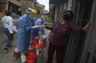 Rosa Gonzales holds onto a door frame as she is tested for the new coronavirus during a house-to-house testing drive in the San Juan de Miraflores neighborhood of Lima, Peru, Tuesday, July 7, 2020. Peru was the first country in Latin America to impose widespread quarantine, which began on March 16. (AP Photo/Martin Mejia)