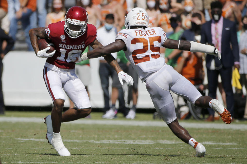 Oklahoma wide receiver Theo Wease (10) evades a tackle by Texas defensive back B.J. Foster (25) during an NCAA college football game in Dallas, Saturday, Oct. 10, 2020. (AP Photo/Michael Ainsworth)