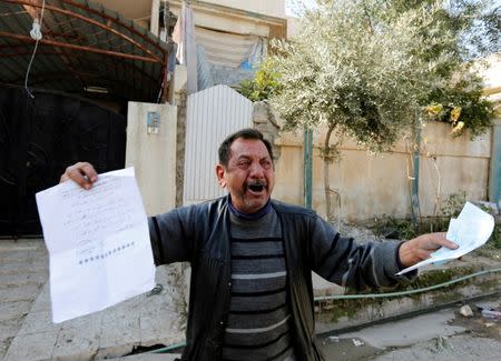 Abu Wissam, whose wife and son were killed by Islamic State militants, cries as he holds up the militants' execution order for his son, east of Mosul, Iraq, January 11, 2017. REUTERS/Ahmed Saad