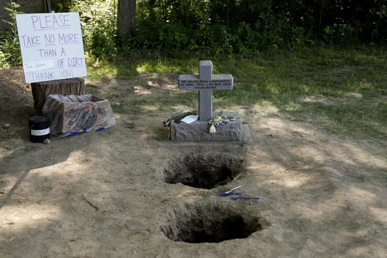 People collect dirt from the grave site of Sister Wilhelmina Lancaster on May 28.