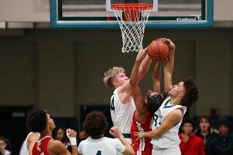 New Bedford's Damarius Roberts is stuck in the middle of Dartmouth's Hunter Matteson and Donovan Burgo fighting for the rebound. Dartmouth High School boys basketball team beat New Bedford High School at home.