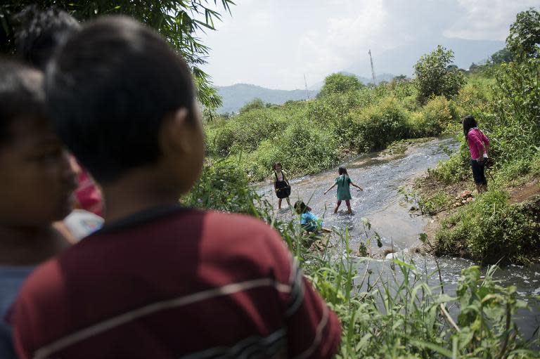 Indonesian children play in Cikijing river, polluted with textile industrial waste, in Rancaekek district, on western Java island, on March 22, 2015