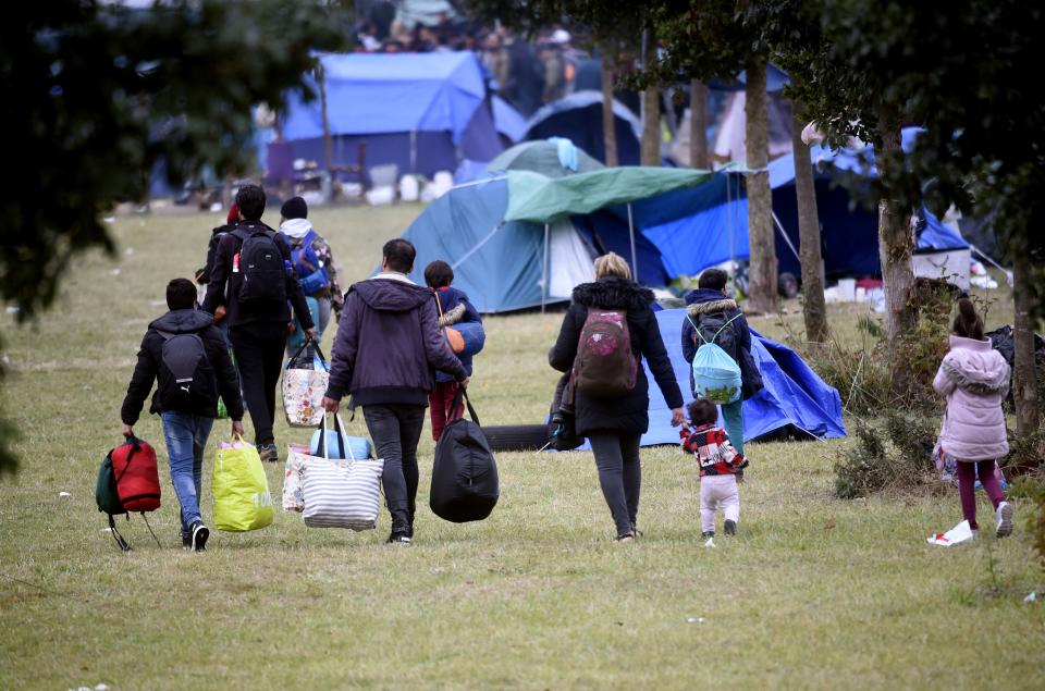 Migrant families leave the camp with their belongings during an evacuation by French police