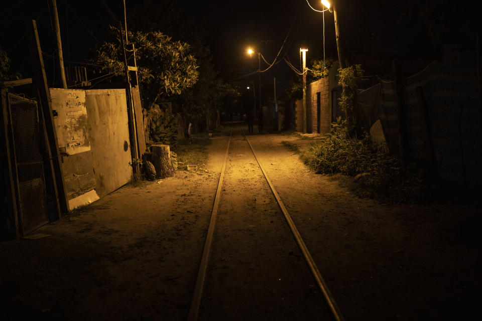 A railway line runs past homes in Villa Banana, a poor neighborhood with high rates of robbery and murder in Rosario, Argentina, Friday, Dec. 3, 2021. The city of some 1.3 million people has high levels of poverty and crime, where violence between gangs who seek to control turf and drug markets has helped fill its prisons. (AP Photo/Rodrigo Abd)