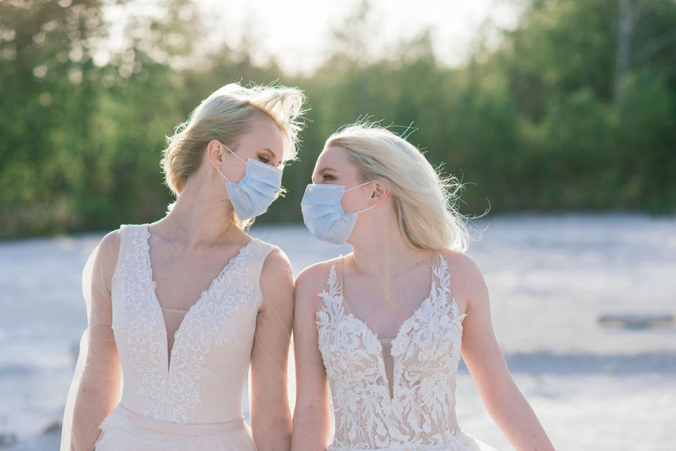 Two brides look at each other while wearing face masks