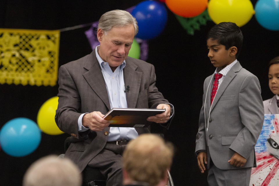 Gov. Greg Abbott receives a photo book by Steven Tippett titled, Midland Oil and Love from Apaar Gutta, at the Midland Chapter of the Republican National Hispanic Assembly's Reagan Lunch at the Bush Convention Center Friday, Nov. 5, 2021, in Midland, Texas. (Jacob Ford/Odessa American via AP)