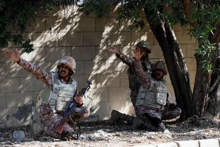 Paramilitary soldiers take cover behind a wall during an attack on the Chinese embassy, where blasts and shots are heard, in Karachi, Pakistan November 23, 2018. REUTERS/Akhtar Soomro