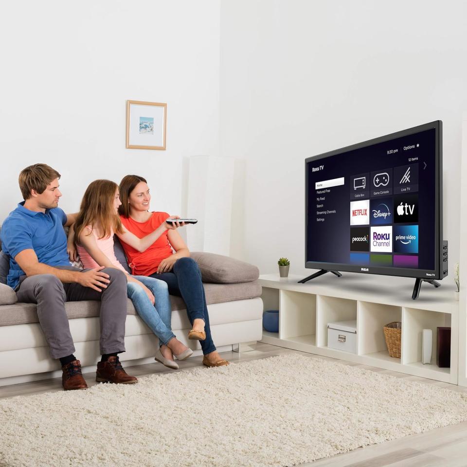 a family sitting on a couch watching the amazon roku tv