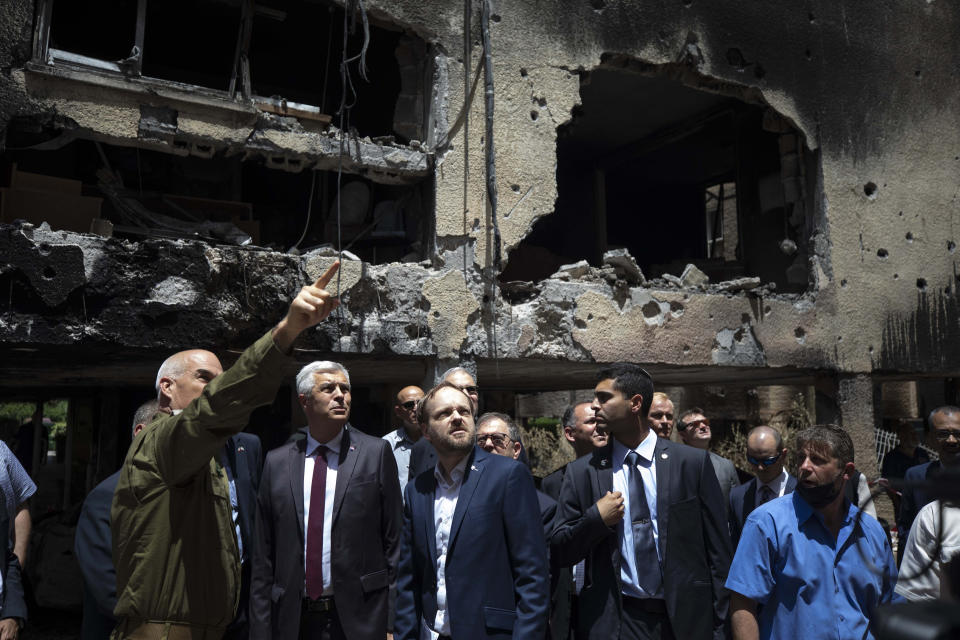 Slovakia's Foreign Minister Ivan Korcok, second left, and Czech Foreign Minister Jakub Kulhanek, center, visit the site of a rocket attack in the central Israeli city of Petah Tikvah, Thursday, May 20, 2021. Heavy airstrikes pummeled a street in the Jabaliya refugee camp in northern Gaza, destroying ramshackle homes with corrugated metal roofs nearby. The military said it struck two underground launchers in the camp used to fire rockets at Tel Aviv. (AP Photo/Sebastian Scheiner)