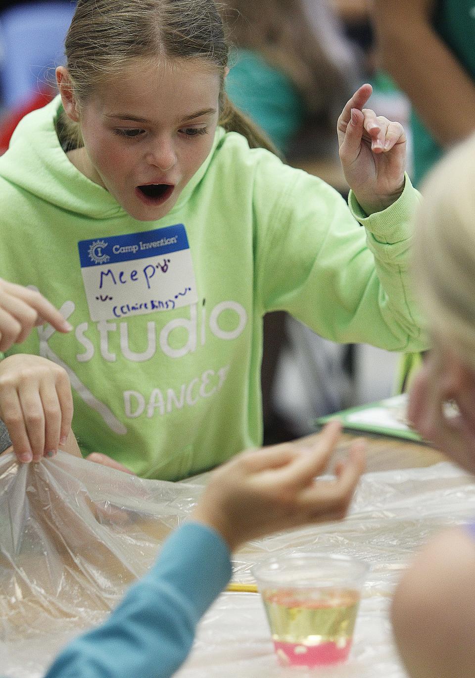 Claire Bills, 10, reacts after dropping an Alka-Seltzer tab into an oil and pink water mixture to create "lava" June 9. This experiment was used to give campers an idea of the conditions on Io, one of Jupiter's moons.