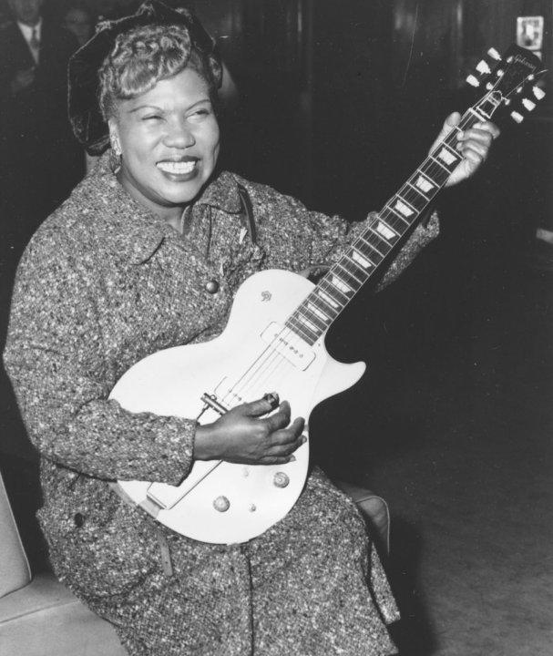 FILE- In this Nov. 21, 1957, file photo, Sister Rosetta Tharpe, guitar-playing American gospel singer, gives an inpromptu performance in a lounge at London Airport, following her arrival from New York. Tharpe, who died in 1973, will be inducted with the “Award for Early Influence” to the Rock and Roll Hall of Fame on April 14, 2018 in Cleveland, Ohio. (AP Photo, File)