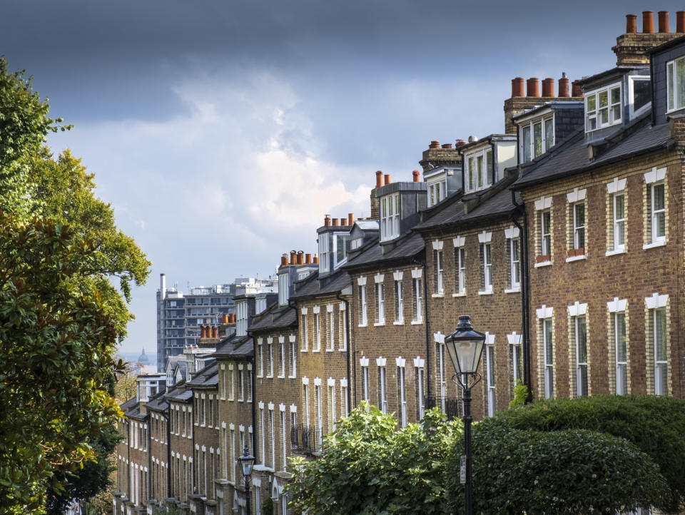 United Kingdom, London, Hampstead village. A view down a steep street of 18th Century Georgian terraced houses with sash windows in Hampstead, a suburb in North London. The Royal Free Hospital, the dome of St. Paul's cathedral and downtown London are visible in the distance