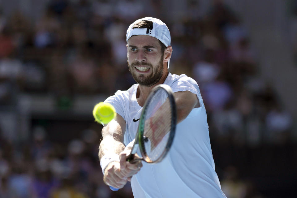 Karen Khachanov devuelve ante Yoshihito Nishioka durante los octavos de final del Abierto de Australia, el domingo 22 de enero de 2022, en Melbourne. (AP Foto/Ng Han Guan)