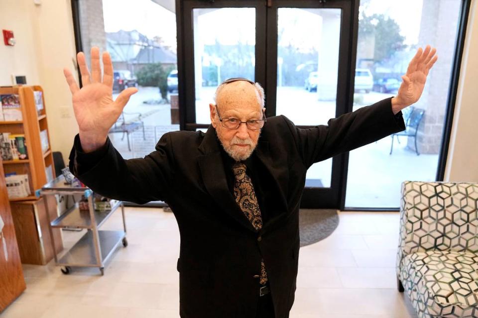 In this Dec. 22, 2022, photo, as Lawrence Schwartz poses for a photo inside of Congregation Beth Israel, he placed his hands in the air and said, “This is what I did when I approached the door,” after he was told he was being released from the hostage situation in Colleyville, Texas.