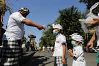 A security guard checks the body temperature of children at a temple amid new coronavirus outbreak in Bali, Indonesia Saturday, July 4, 2020. (AP Photo/Firdia Lisnawati)