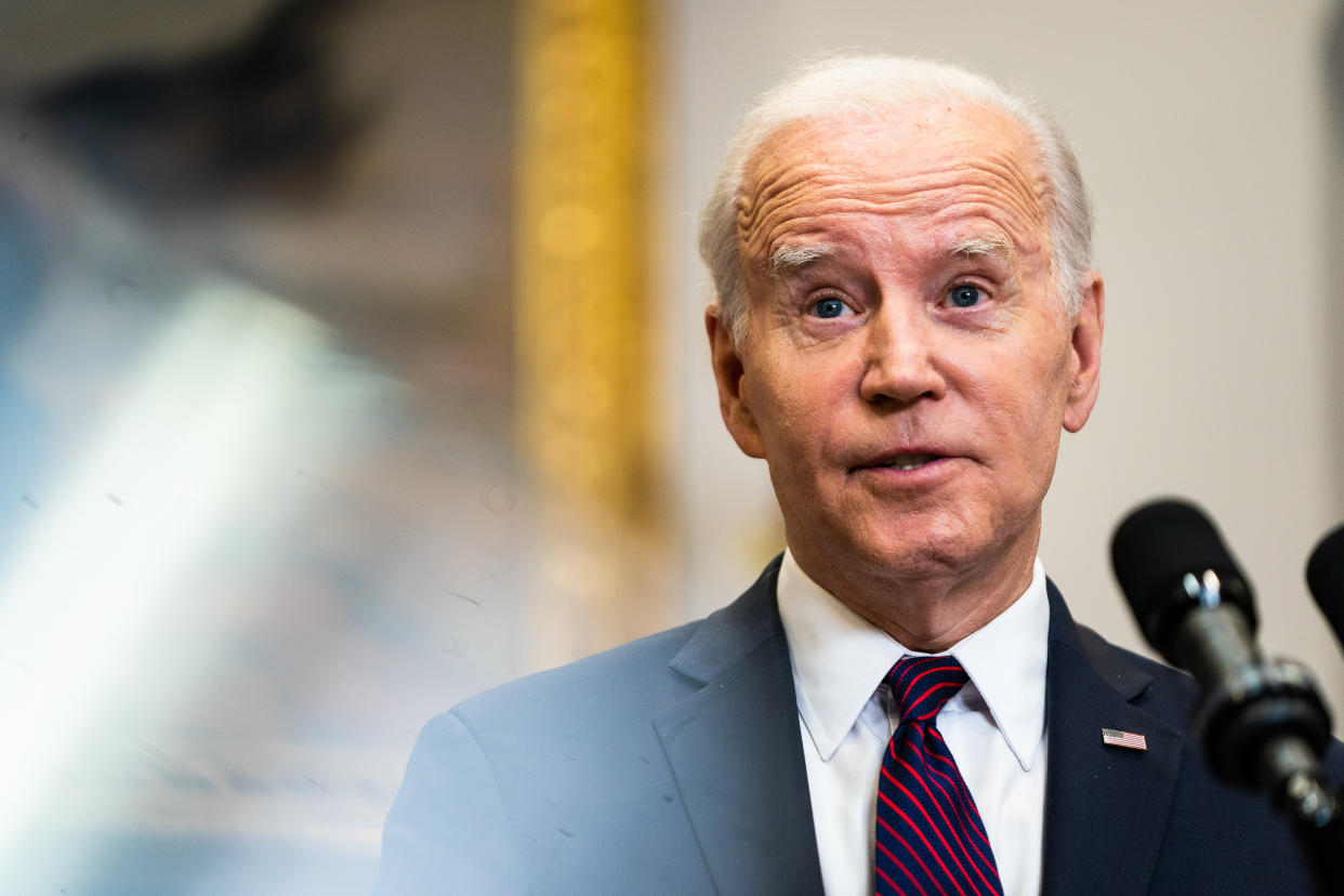 President Biden speaking into microphones at a podium.