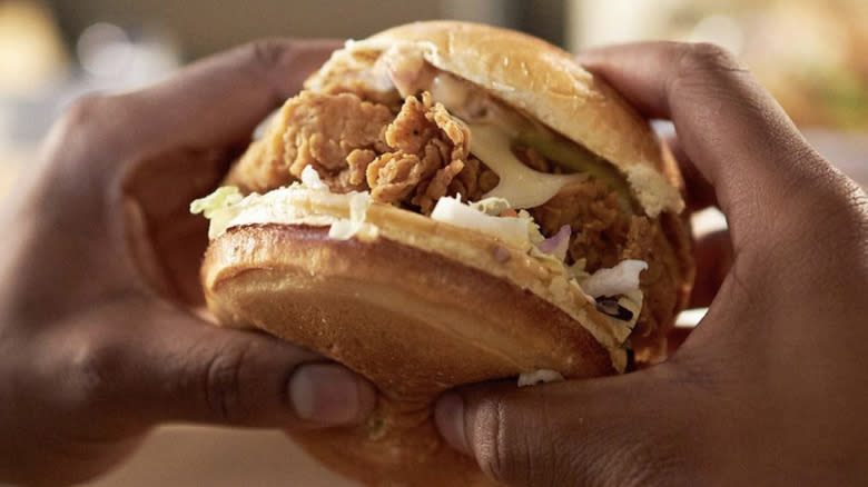 Hands holding chicken sandwich 