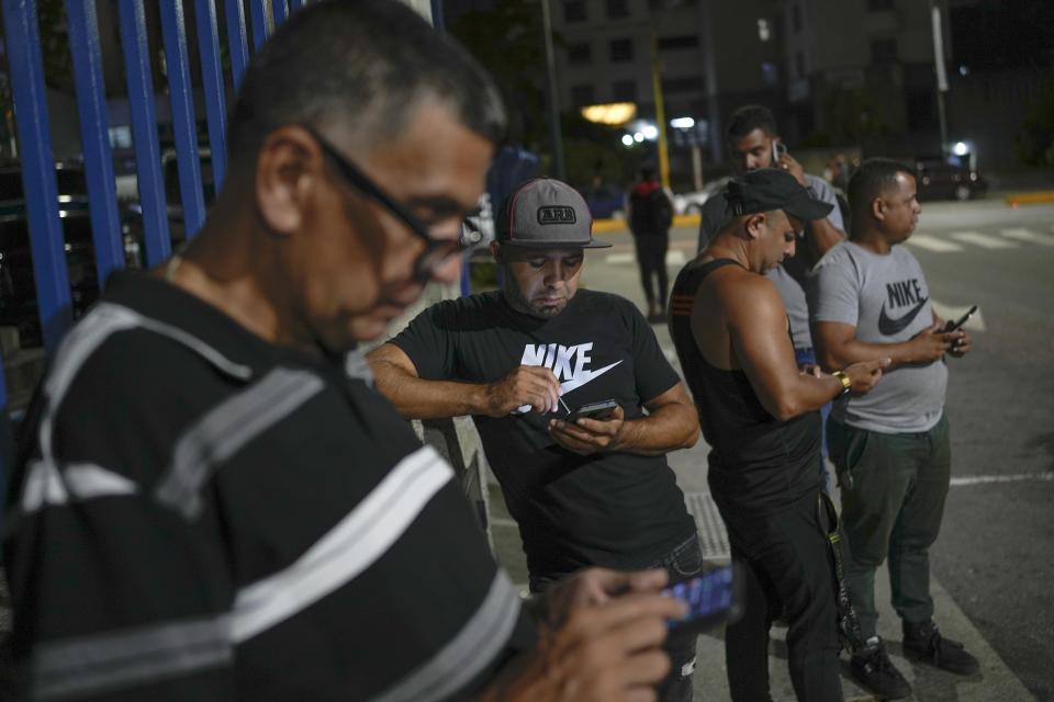 Ridery drivers monitor their cell phones for customers near a mall in Caracas, Venezuela, Thursday, May 5, 2022. Ridery is one of at least three Venezuelan ride-sharing apps that launched during the pandemic — and which have taken advantage of a de facto switch of currencies from the Venezuelan bolivar to the U.S. dollar. (AP Photo/Matias Delacroix)
